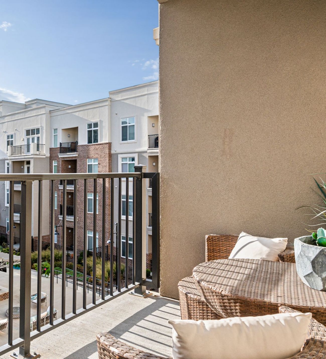 Domain City Center A balcony with wicker and patio furniture overlooking a garden.