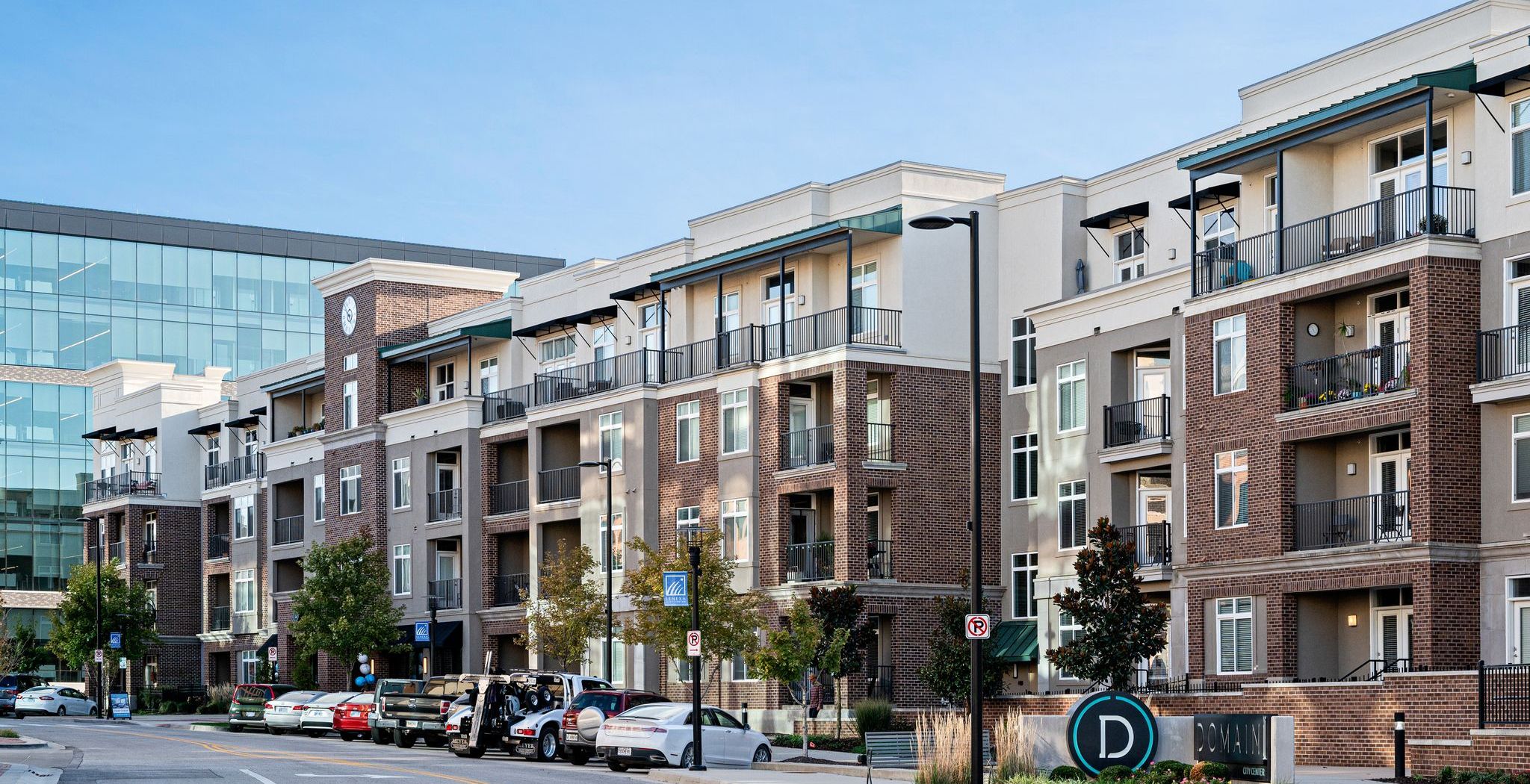 Domain City Center A large apartment complex with a parking lot in front, surrounded by trees and greenery.