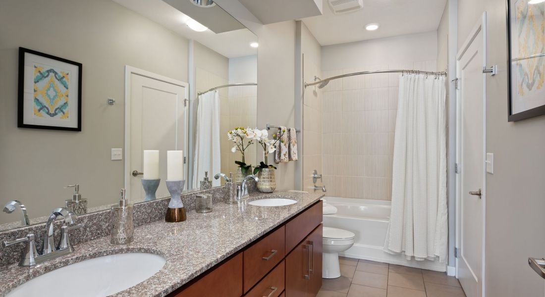 Domain City Center A bathroom with two sinks and a tub, perfect for a couple's morning routine.